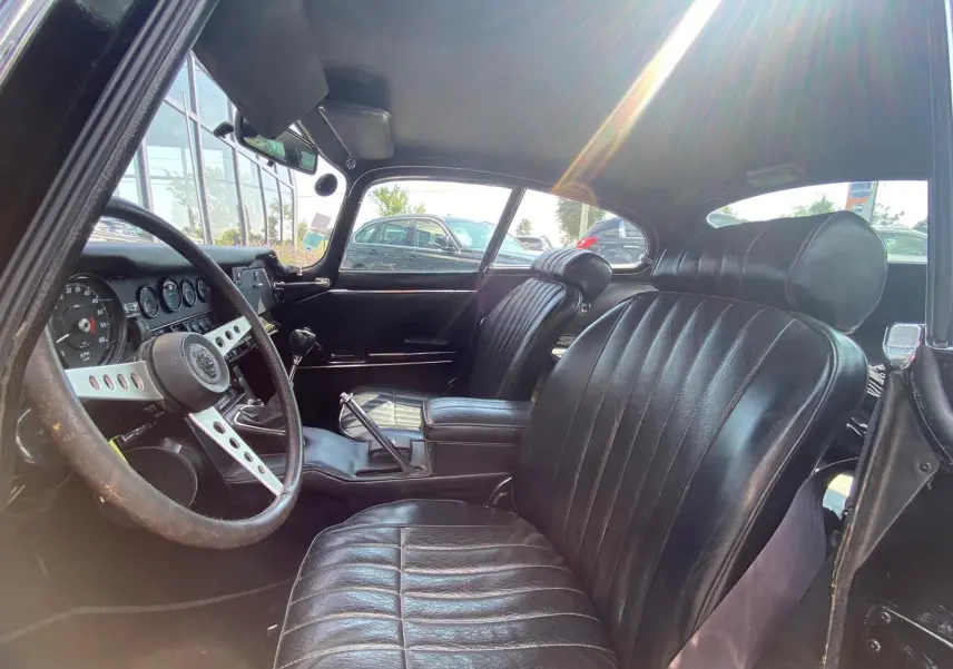 Intérieur noir du Jaguar S-Type Type E Coupé 4.2 Série 2 de 1970, vue côté conducteur montrant le volant et les sièges en cuir.