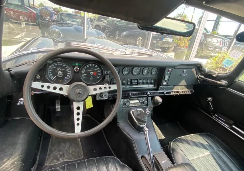 Intérieur noir de la Jaguar S-Type 1970, vue du poste de conduite avec tableau de bord vintage et volant trois branches.
