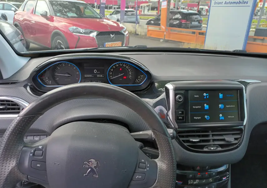 Vue intérieure du tableau de bord et volant de la Peugeot 2008 blanc, avec écran tactile et compteur digital.