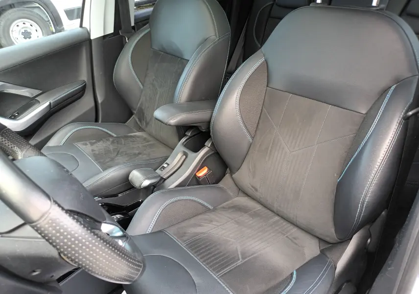 Vue intérieure côté conducteur du Peugeot 2008 blanc de 2018, mettant en valeur les sièges sport noirs avec surpiqûres bleues.