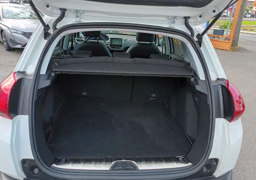 Coffre ouvert vu de l'arrière d'un Peugeot 2008 blanc, montrant l'espace de chargement et l'intérieur noir.
