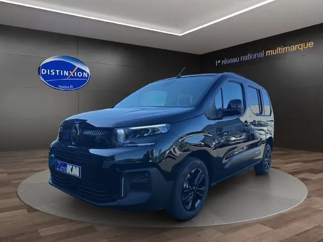 Vue 3/4 avant d'un Citroën Berlingo noir 2025 avec jantes noires et calandre moderne dans un showroom.