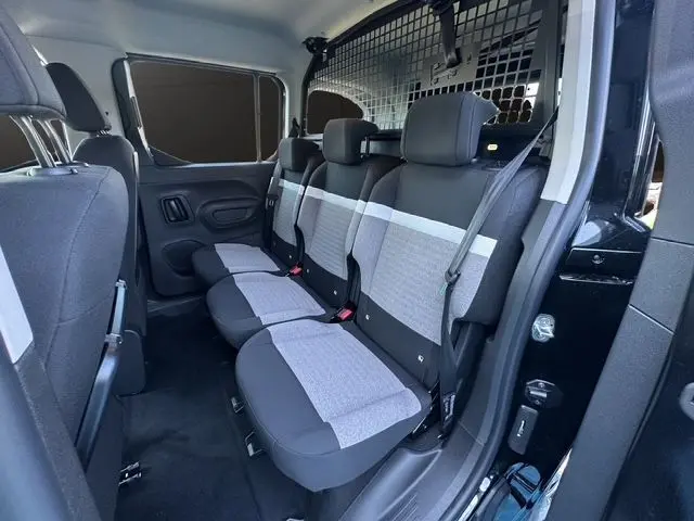 Vue intérieure côté droit du Citroën Berlingo N1 2025, sièges arrière gris et noir avec cloison métallique de séparation.