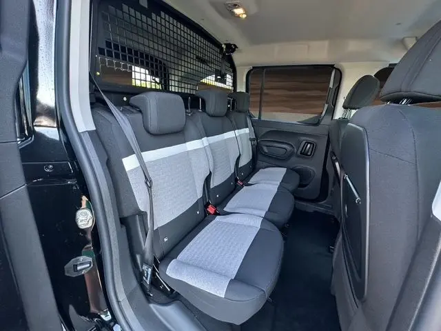 Vue intérieure côté gauche du Citroën Berlingo noir 2025, montrant la banquette arrière trois places avec séparation métallique.