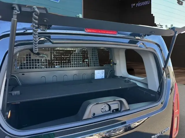 Vue arrière ouverte du Citroën Berlingo noir 2025, montrant l'espace de chargement avec cloison métallique et hayon relevé.