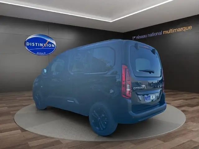 Vue 3/4 arrière droite d'un Citroën Berlingo noir 2025 avec jantes noires et hayon dans un showroom intérieur.