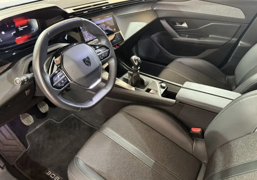 Intérieur de la Peugeot 308 2023, vue côté conducteur, volant cuir, boîte manuelle et écran tactile central.