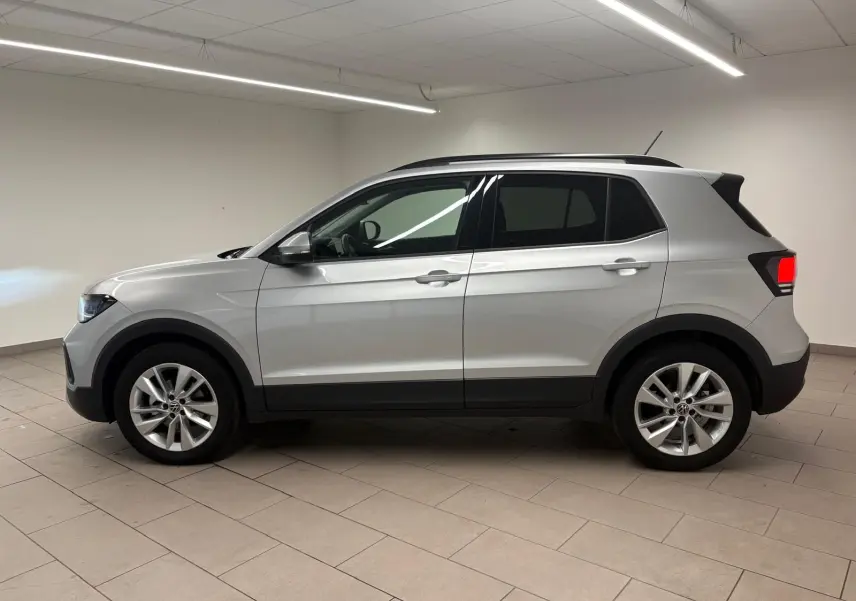 Vue de profil côté gauche d'un Volkswagen T-Cross 2024 en reflet d'argent, avec jantes alliage et vitres surteintées.