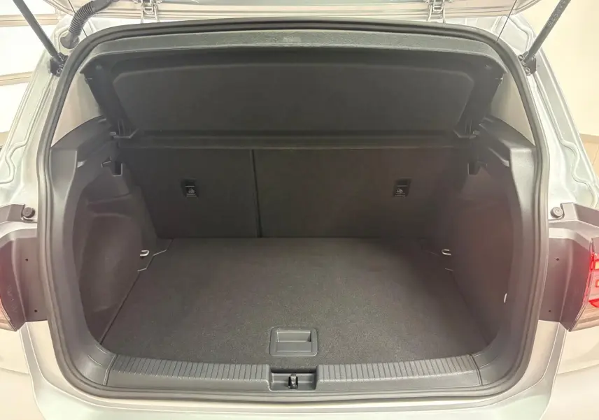 Coffre ouvert vu de l'arrière d'un Volkswagen T-Cross 2024 reflet d'argent, intérieur noir et espace de chargement vide.