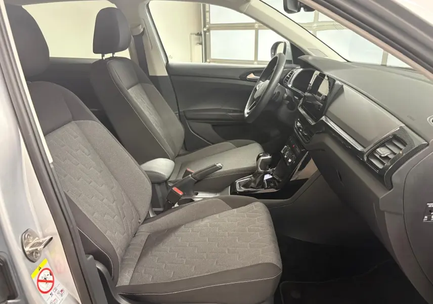 Intérieur avant du Volkswagen T-Cross 2024 en reflet d'argent, montrant sièges tissu gris et tableau de bord noir.