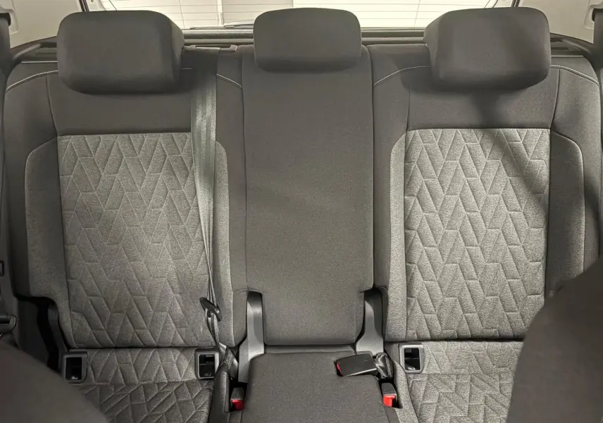 Vue intérieure arrière du Volkswagen T-Cross 2024, sièges tissu gris avec motifs géométriques et appuis-tête intégrés.