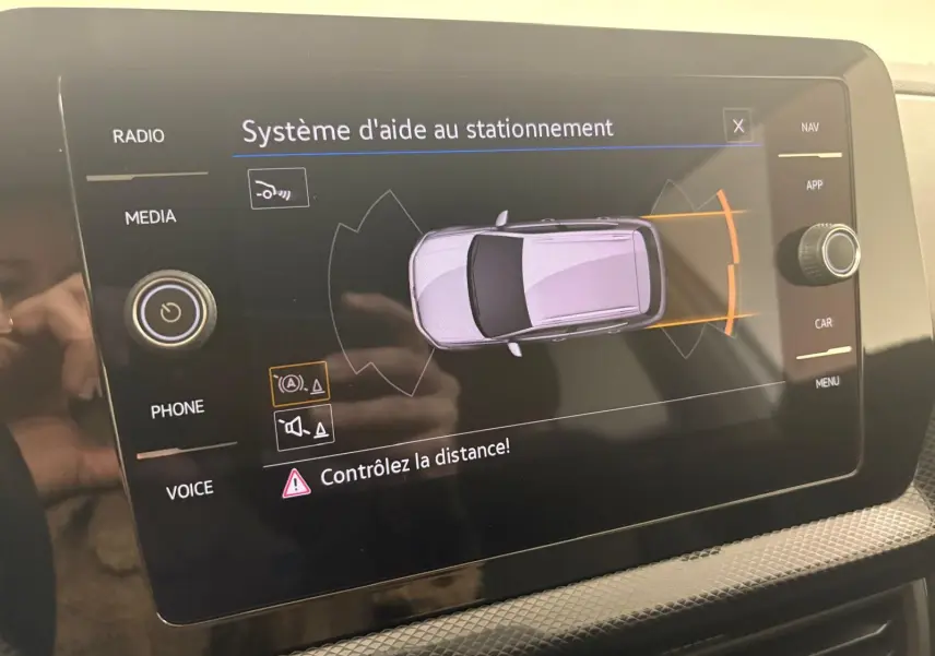 Écran tactile intérieur montrant le système d'aide au stationnement du Volkswagen T-Cross 2024 en vue de dessus du véhicule.