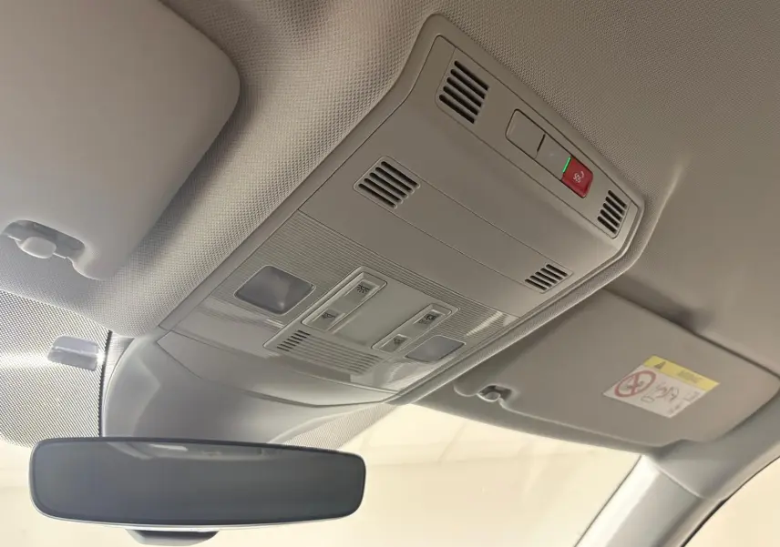 Vue intérieure du plafonnier gris clair avec commandes et rétroviseur dans un Volkswagen T-Cross 2024 reflet d'argent.