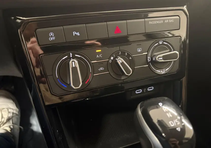 Vue rapprochée de la console centrale noire avec commandes de climatisation manuelle et levier de vitesse automatique du Volkswagen T-Cross.