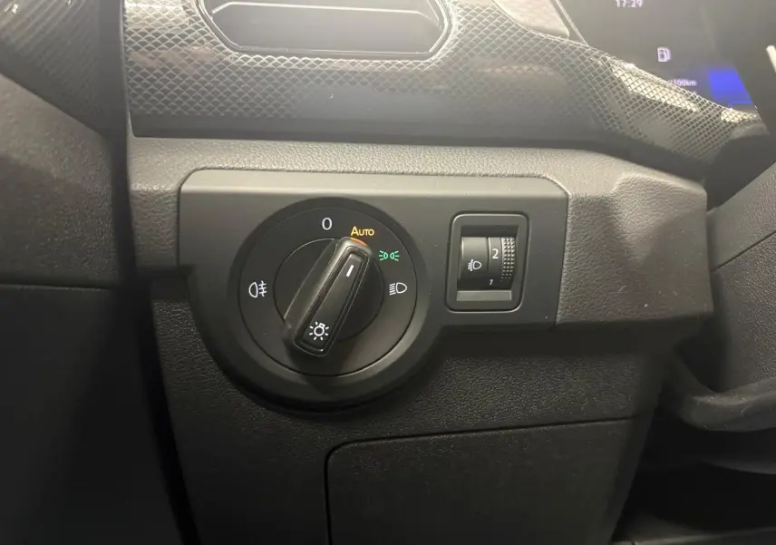 Gros plan sur le bouton de commande des phares et réglage d'intensité dans l'habitacle noir du Volkswagen T-Cross 2024.
