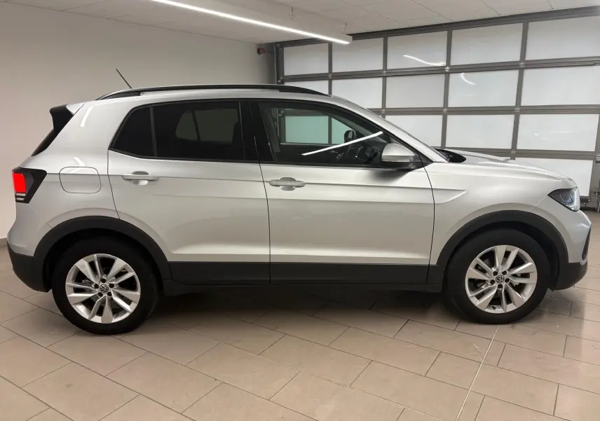 Vue de profil côté gauche d'un Volkswagen T-Cross 2024 argenté avec jantes alliage et vitres teintées.