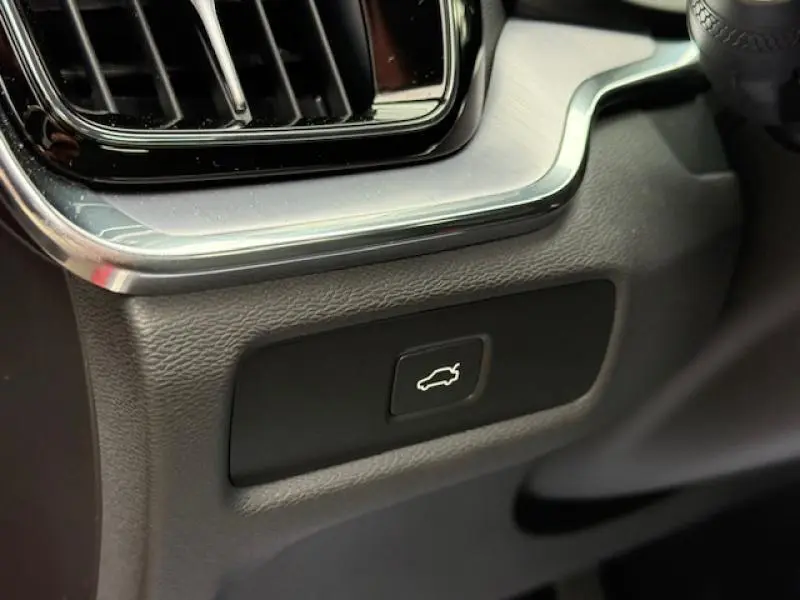 Gros plan sur le bouton d'ouverture du coffre dans l'habitacle d'une Volvo S60 Rouge Fusion Métallisé 2024.