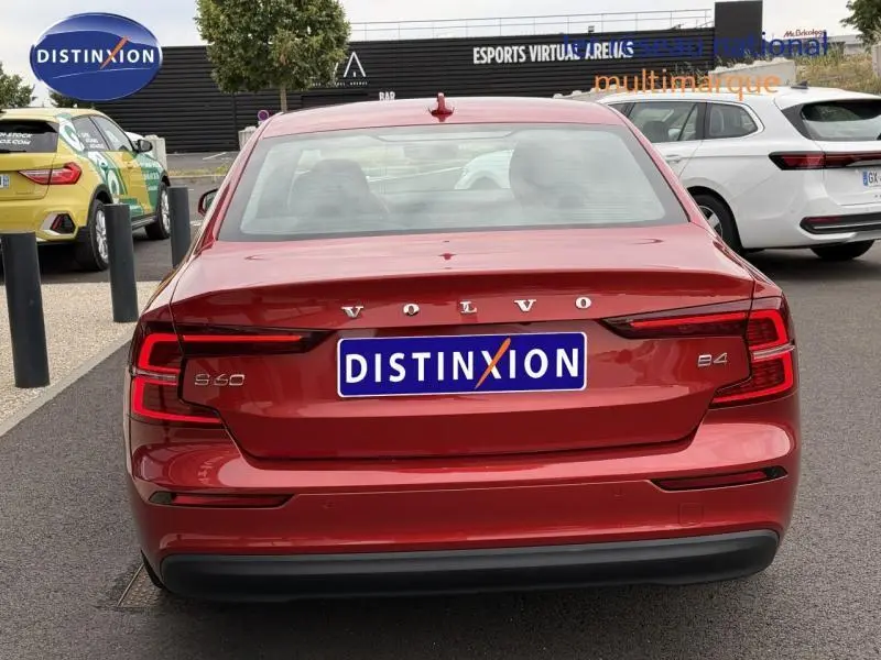 Vue arrière d'une Volvo S60 2024 rouge fusion métallisé avec logo et plaques distinctives visibles.