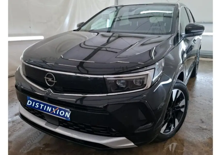 Opel Grandland noir vue 3/4 avant droit en showroom avec jantes alliage bicolores et logo Distinxion.