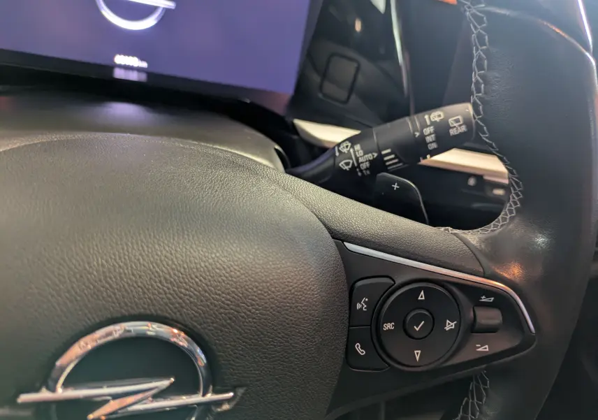 Gros plan sur le volant noir de l'Opel Grandland 2023 avec commandes audio et manette d'essuie-glace visible.