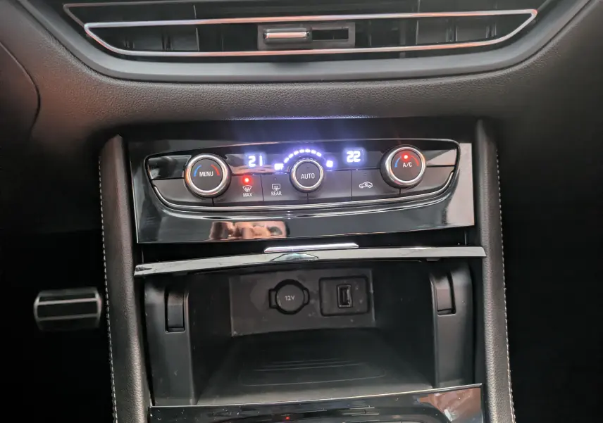 Détail de la console centrale noire de l’Opel Grandland 2023, avec commandes de climatisation automatique 2 zones et prise 12V.
