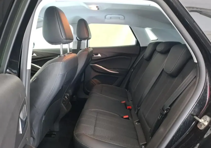 Coffre ouvert vu de l'arrière d'un Opel Grandland noir 2023, montrant un espace de chargement propre et éclairé.