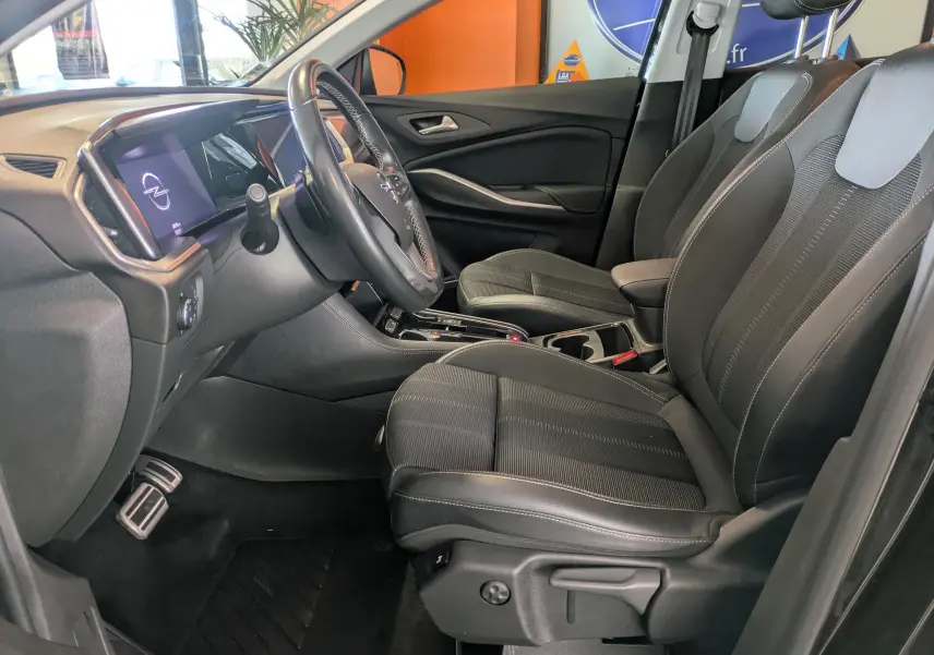 Vue intérieure côté conducteur de l’Opel Grandland 2023, sièges noirs et tableau de bord avec écran tactile allumé.