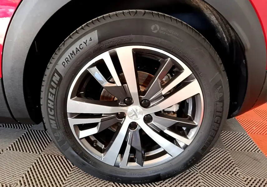 Gros plan sur la roue avant droite du Peugeot 3008 hybride rechargeable rouge, avec jante alliage et pneu Michelin.