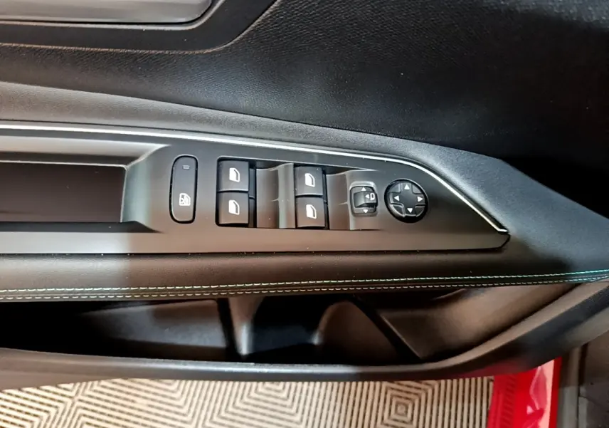 Gros plan sur la commande des vitres et rétroviseurs côté conducteur du Peugeot 3008 hybride rechargeable, intérieur noir avec surpiqûres bleues.