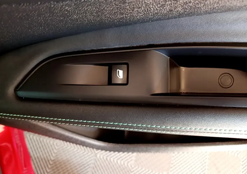 Gros plan sur la commande de lève-vitre côté conducteur avec surpiqûres vertes sur la portière noire du Peugeot 3008 hybride.