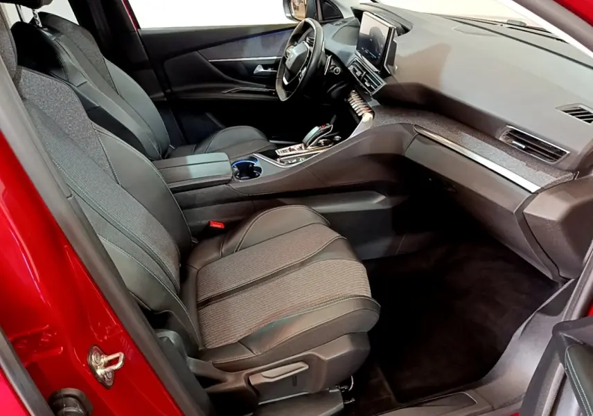 Vue intérieur côté passager avant du Peugeot 3008 hybride rechargeable 2021 avec sièges tissu et cuir noirs et tableau de bord moderne.