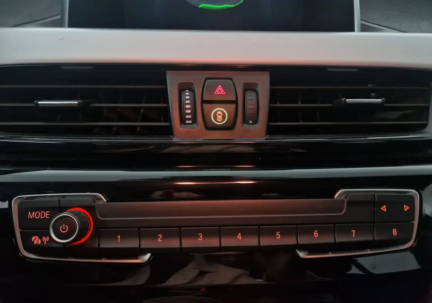 Gros plan sur la console centrale noire du BMW X2 gris clair, montrant les boutons de commande et les aérateurs.