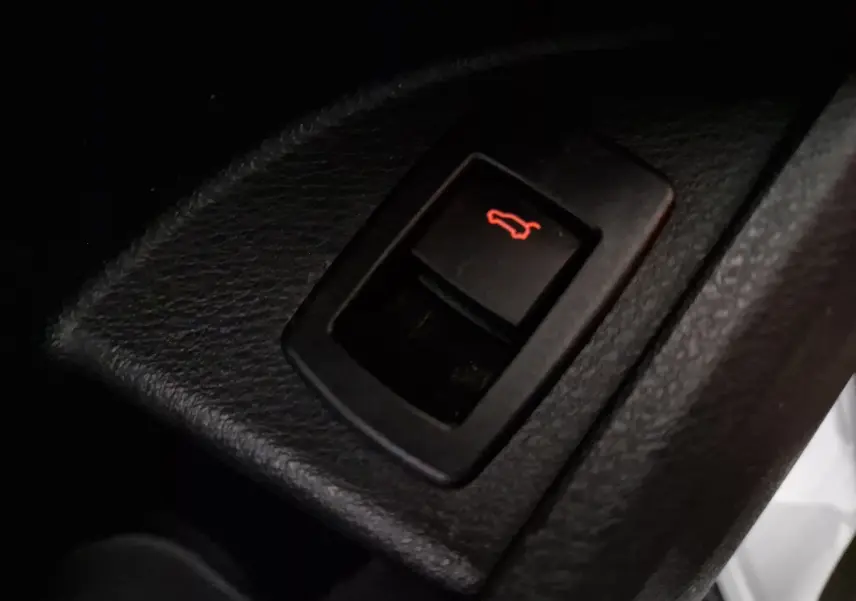 Gros plan sur le bouton d'ouverture du coffre intérieur d'une BMW X2 gris clair métal, version 2018.