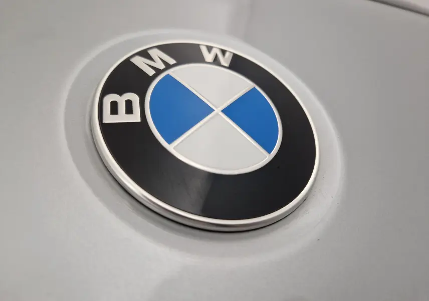 Gros plan sur l'emblème BMW en relief sur la carrosserie gris clair métallisé du SUV X2.