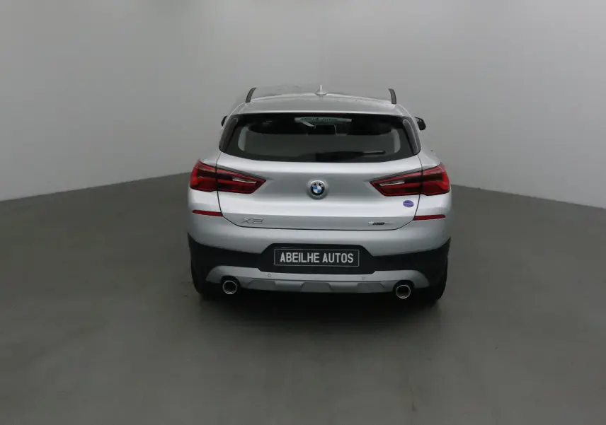 Vue arrière d'une BMW X2 gris clair métal de 2018 avec double sortie d'échappement et logo visible sur un fond neutre.