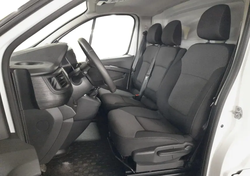 Vue intérieure côté conducteur du Renault Trafic blanc 2024, montrant la banquette 3 places et le tableau de bord noir.