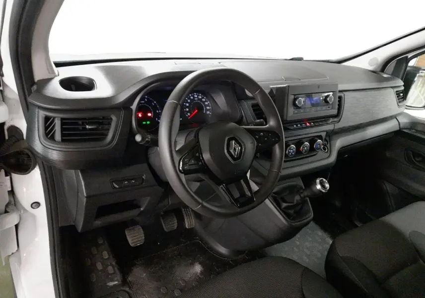 Vue intérieure côté conducteur du Renault Trafic Fourgon blanc 2024, tableau de bord et volant multifonctions visibles.