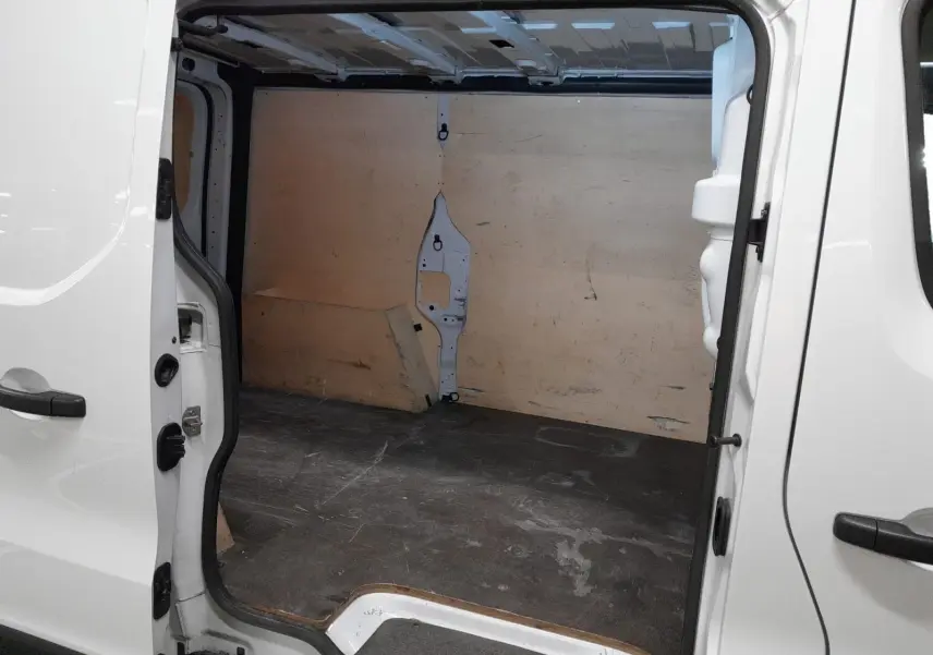 Vue intérieure du Renault Trafic Fourgon blanc 2024, montrant l'espace de chargement avec porte latérale droite ouverte.