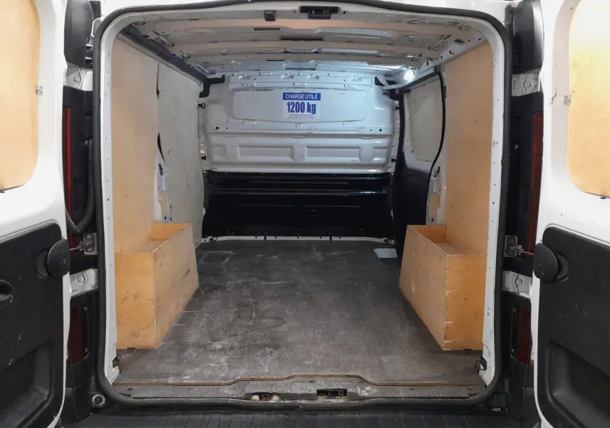 Vue arrière intérieure du Renault Trafic Fourgon blanc avec espace de chargement équipé de protections en bois.