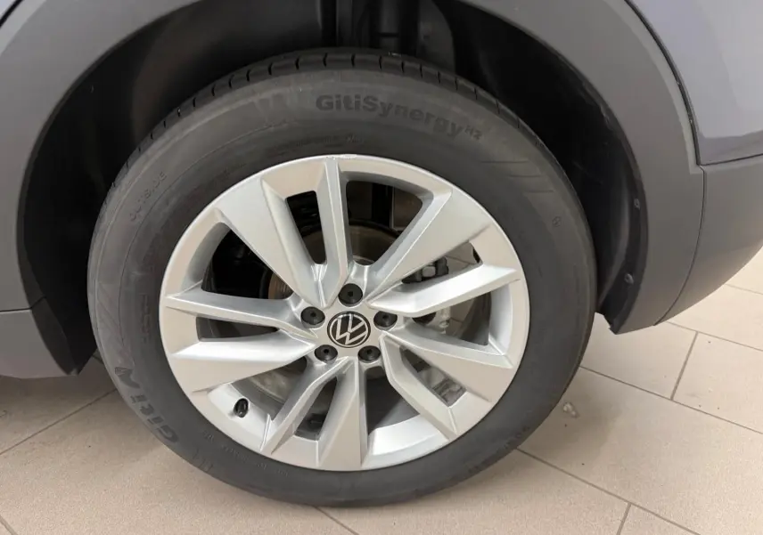 Gros plan sur la roue avant droite d’un Volkswagen T-Cross gris cendre, mettant en valeur la jante alliage et le pneu GitiSynergy.