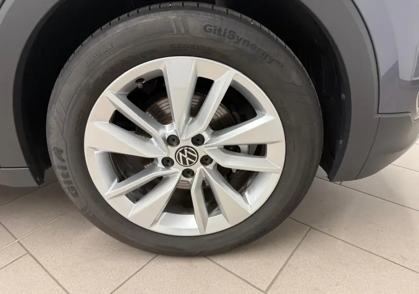 Gros plan sur la roue avant gauche du Volkswagen T-Cross gris cendre, mettant en valeur la jante alliage à 10 branches.