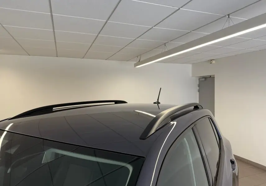 Vue en plongée du toit noir brillant et des barres de toit sur le côté droit du Volkswagen T-Cross gris cendre 2025.