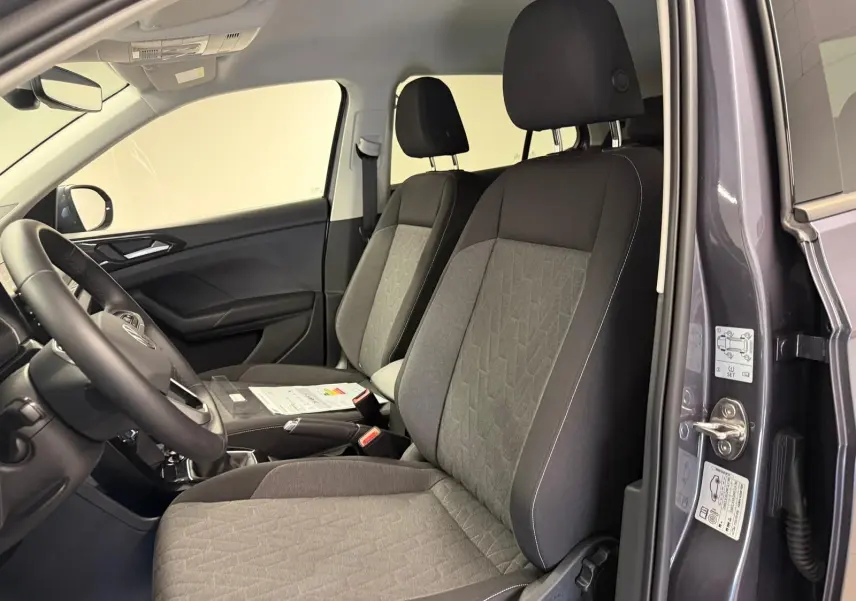 Intérieur du Volkswagen T-Cross gris cendre 2025, vue côté conducteur ouverte, sièges tissu gris avec motifs géométriques.