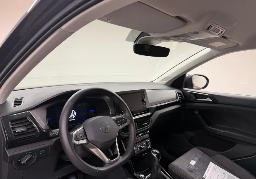 Vue intérieure côté conducteur du Volkswagen T-Cross gris cendre 2025, avec volant multifonction et écran tactile central.