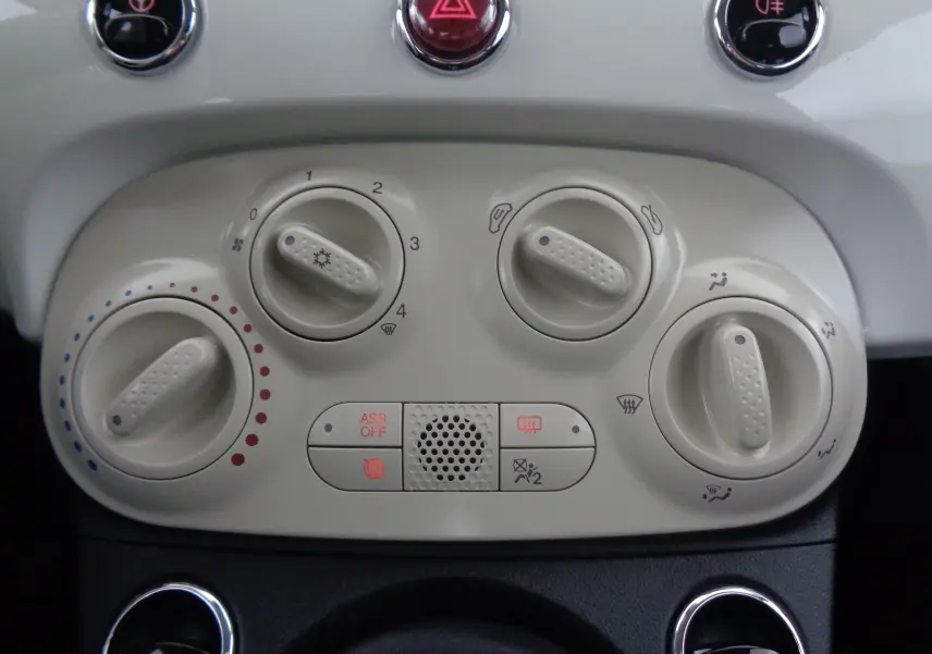 Gros plan sur les commandes de climatisation blanches du tableau de bord d'une FIAT 500 Blanc Gelato 2023.
