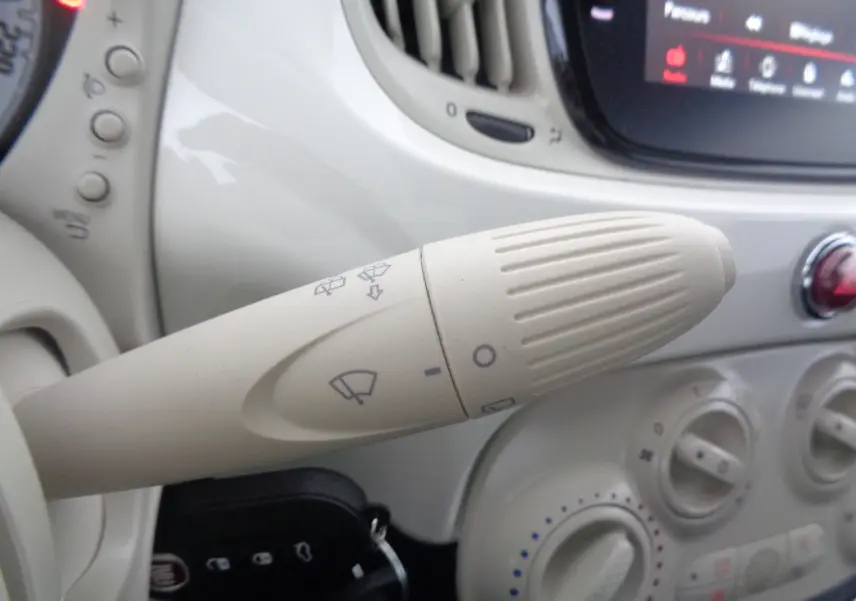 Gros plan sur la manette d'essuie-glace beige du tableau de bord blanc gelato de la Fiat 500 hybride 2023.