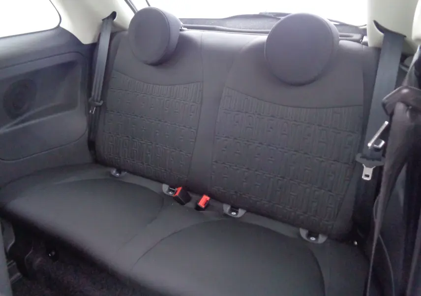 Vue intérieure arrière des sièges noirs de la Fiat 500 1.0 Hybrid 2023 avec motifs FIAT embossés sur le tissu.