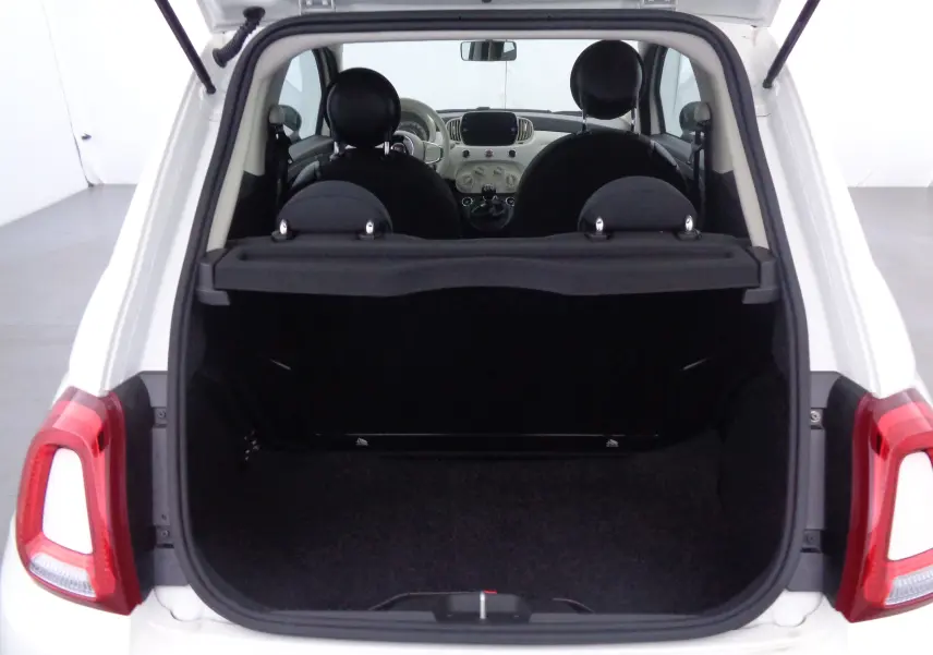 Vue arrière ouverte du coffre d'une FIAT 500 blanc gelato 2023, montrant l'intérieur et les sièges noirs.