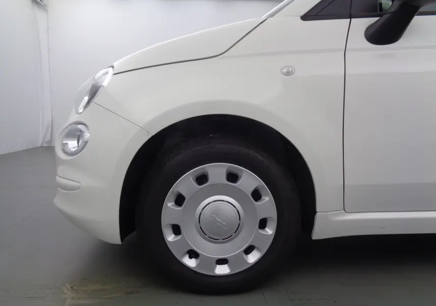 Gros plan sur la roue avant gauche d'une FIAT 500 blanc gelato, mettant en valeur la jante et le phare rond avant.