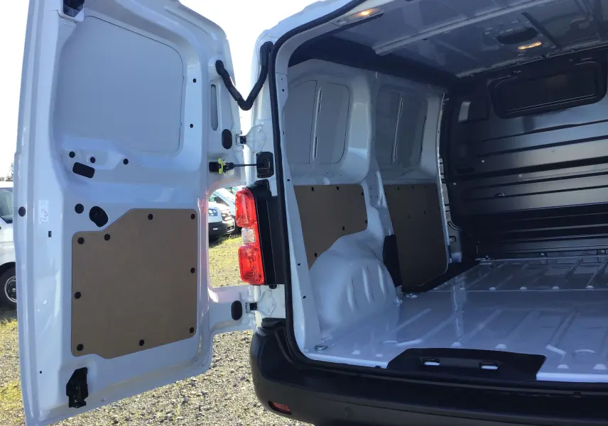 Vue arrière ouverte du Peugeot Expert Fourgon blanc 2024, montrant l'espace de chargement vide avec panneaux de protection en bois.